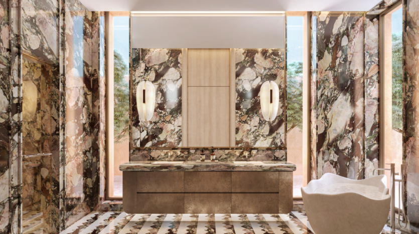 Luxurious bathroom in Asora Bay, Dubai, with large marble motifs on the walls and floor. A double-sink vanity with wood accents and modern pendant fixtures frames a central mirror. Large windows offer plenty of natural light, and an elegant white freestanding bathtub sits in the corner.