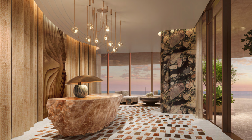 Luxurious interior with a large marble reception counter, artistic wall decoration and modern lighting fixtures. The room features high windows offering breathtaking views of Dubai's Asora Bay, overlooking the ocean and the sunset with elegant decor highlighting the coastal ambience.