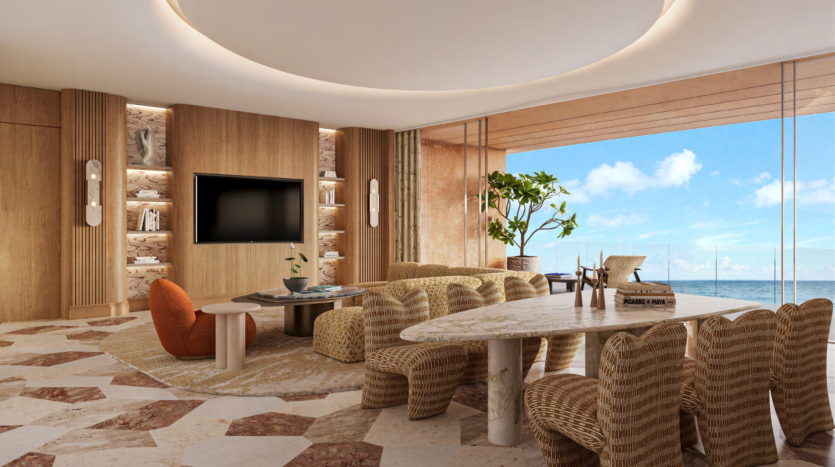 A luxurious living room with a large window offering breathtaking views of Asora Bay, Dubai. The space includes a modern TV, comfortable seating, a long dining table with wicker chairs, wooden walls and a neutral-toned carpet. A potted plant adds a touch of greenery.