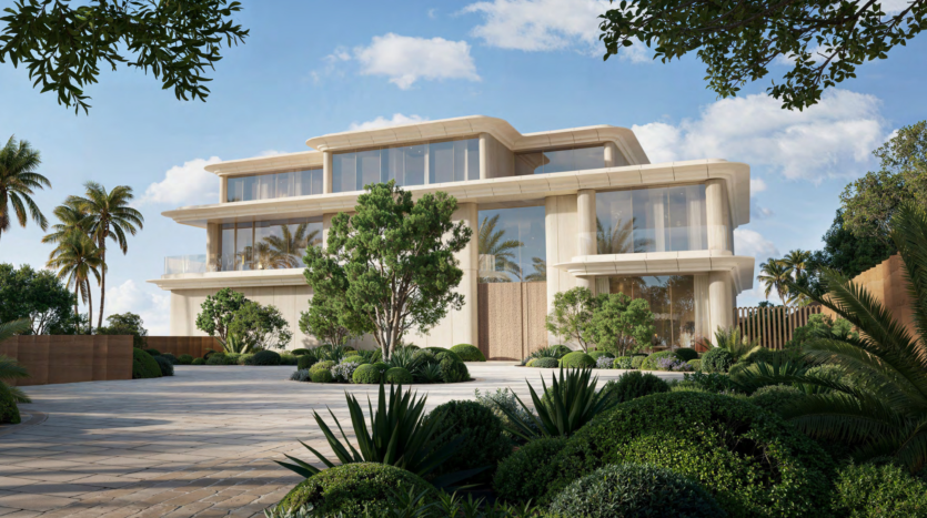 Luxurious modern mansion with large bay windows and multiple floors, nestled in Dubai's opulent Asora Bay. Surrounded by lush landscaping with brightly colored palms and shrubs, the light-colored exterior stands elegantly against a partly cloudy sky.
