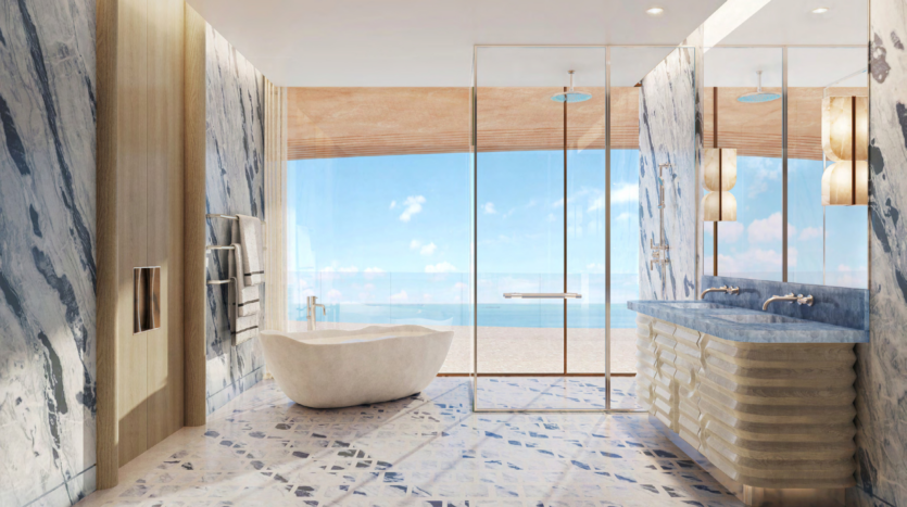 Luxurious bathroom with large marble tiles, freestanding bathtub, two sinks and glass shower. A window overlooks Dubai's magnificent Asora Bay under a clear blue sky.