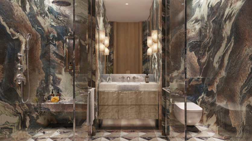 Luxurious bathroom with marble walls and floor, inspired by the elegance of Asora Bay. It features an elegant sink with a large mirror, decorative lights, a glass shower on the left and a toilet on the right. Warm, earthy tones dominate this Dubai-style design.