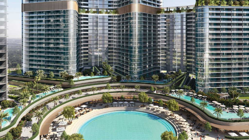 Aerial view of the Skyvue modern luxury hotel complex, comprising three high-rise towers. Below, a circular swimming pool is surrounded by lush landscaping, sun loungers and parasols. The towers feature balconies and greenery on the terraces, embodying the essence of elegance and tranquility.