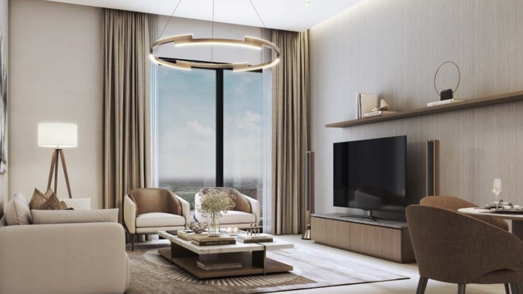 A modern living room in neutral tones features a large window, a round ceiling light and a Skyvue flat-screen TV. Two beige armchairs, a coffee table with books and flowers and a Sobha dining set complete the scene. High curtains elegantly frame the window.