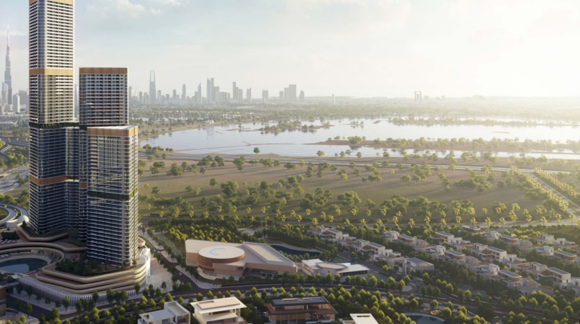 Aerial view of an urban landscape with the SkyVue Spectra skyscrapers dominating the left. The surroundings are composed of lush green parks, scattered buildings and a sparkling body of water. A distant horizon is visible under a clear, misty sky.
