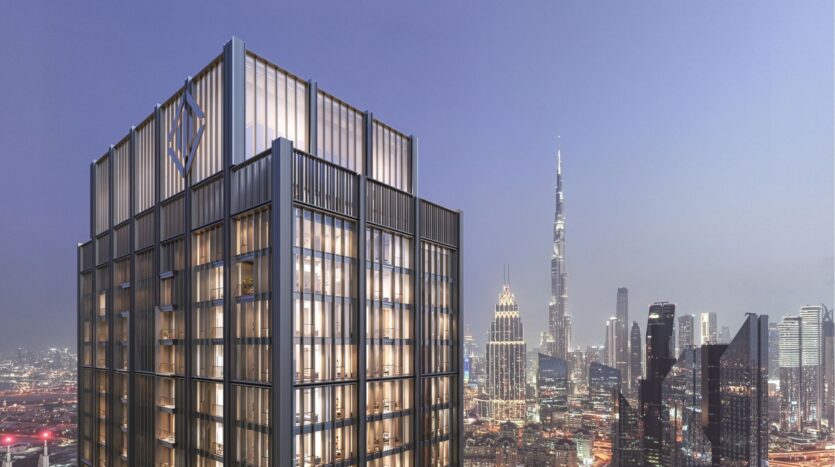 A modern skyscraper with illuminated windows stands proudly on the heights of the DIFC at dusk. In the background, other tall buildings, including a distinctive needle-shaped tower, stand out against the clear sky.