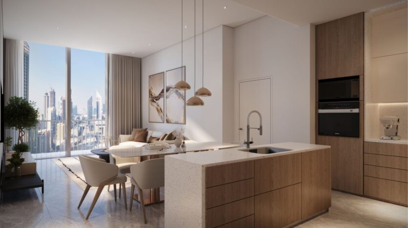 Modern kitchen and dining room with light wood furniture, white island and pendant lights. A large window offers a view of the DIFC Heights cityscape, and the dining table is set near works of art hung on the wall. The floor is polished with a light stone texture.