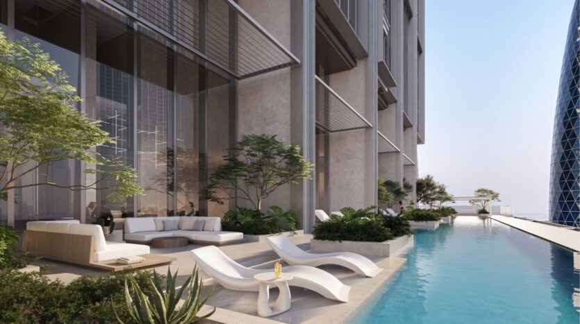 Luxurious outdoor pool area with modern loungers and comfortable seating at DIFC Heights. Surrounded by tall plants, the pool adjoins a contemporary building with large bay windows, offering a relaxing atmosphere under an azure blue sky.