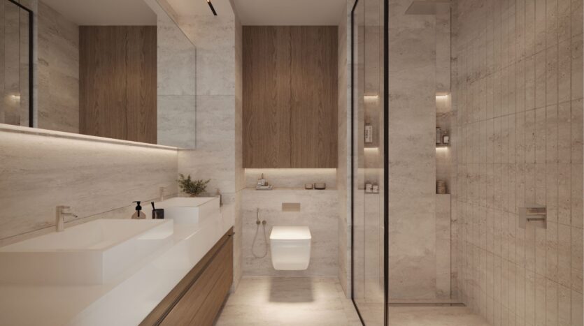 Modern bathroom in DIFC Heights, with large mirrors above a double vanity, and wood accents on drawers and walls. A wall-hung toilet adjoins a glass-enclosed shower. The room is lit by recessed spotlights, creating a warm ambience.
