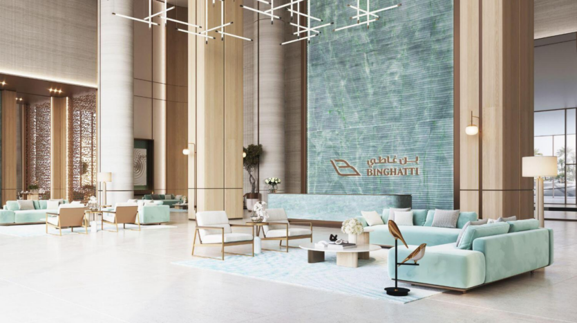 Un vestíbulo espacioso y moderno con techos altos, detalles de madera clara, sofás de color azul pálido y una gran pared texturizada adornada con el logotipo de Binghatti Aquarise en dorado. El espacio es luminoso, con una decoración elegante e iluminación decorativa.