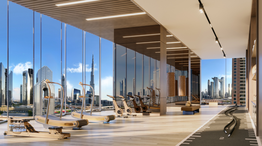 Moderno gimnasio con aparatos de madera, grandes ventanales y pista de atletismo, que ofrece vistas panorámicas de la ciudad con altos rascacielos y el Burj Khalifa a lo lejos.