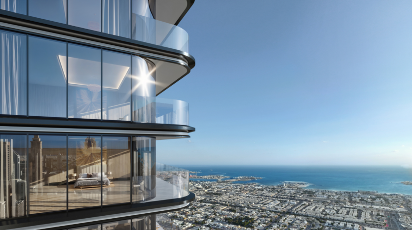 Un moderno rascacielos con balcones acristalados domina una ciudad costera y el mar bajo un cielo azul celeste. La luz del sol se refleja en las ventanas curvas del edificio.