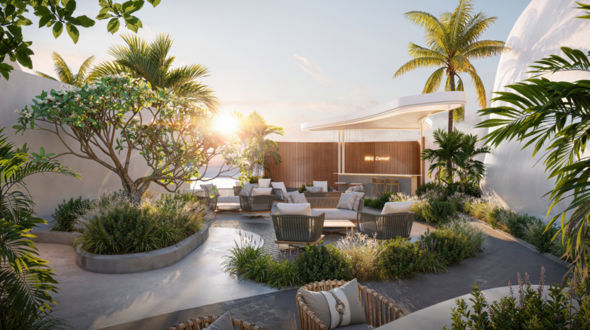 Modern outdoor lounge area with woven chairs and tables surrounded by lush tropical plants, palm trees and an elegant bar under an awning, with sunlight streaming through at sunset near a beach.