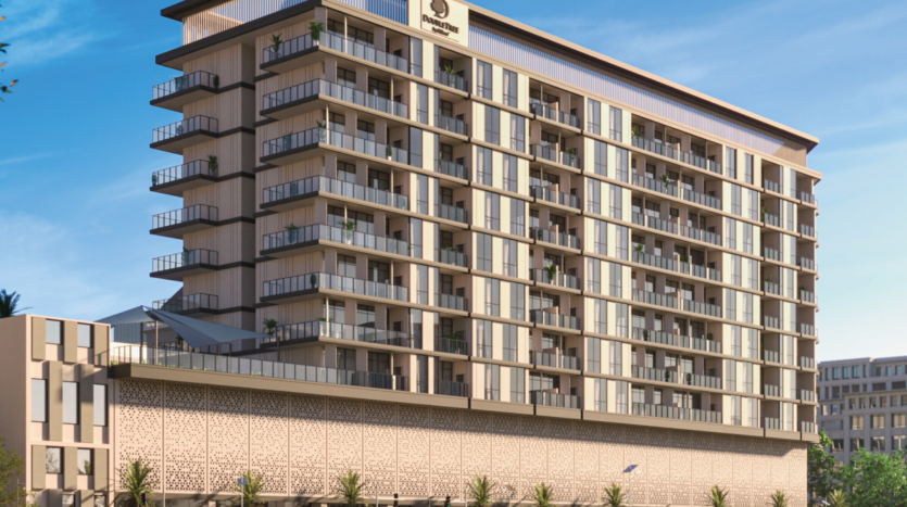 Un moderno edificio multipiano dell'hotel DoubleTree by Hilton Dubai con numerosi balconi, grandi finestre e una facciata decorativa, sullo sfondo di un cielo azzurro e limpido con alcune palme in primo piano.