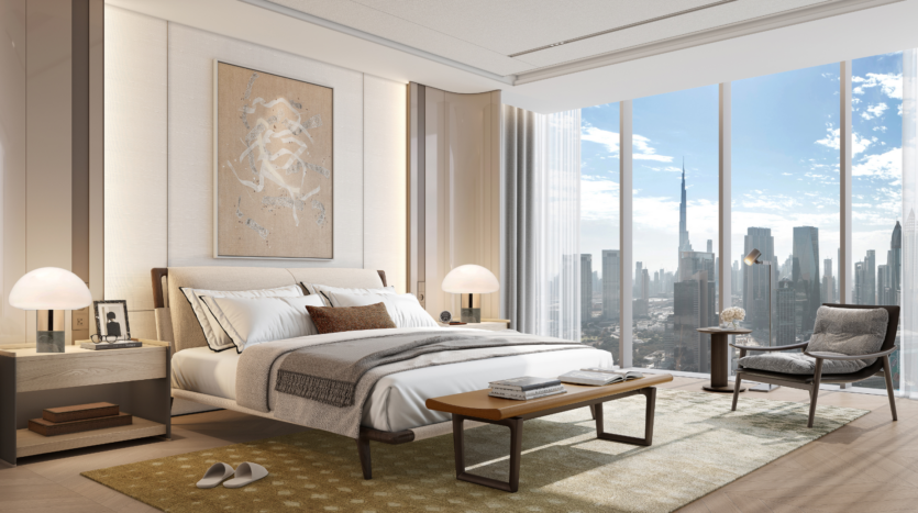 Habitación moderna con grandes ventanales con vistas a los tejados de la ciudad, que incluye una cama cuidadosamente hecha, mesillas de noche con lámparas, una silla cómoda, una mesa de centro, una alfombra y una obra de arte abstracta en la pared encima de la cama.
