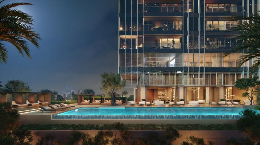 Un moderno bloque de pisos de lujo de noche con una piscina bien iluminada, tumbonas junto a la piscina, palmeras y elegantes asientos al aire libre, con las luces de la ciudad visibles al fondo.