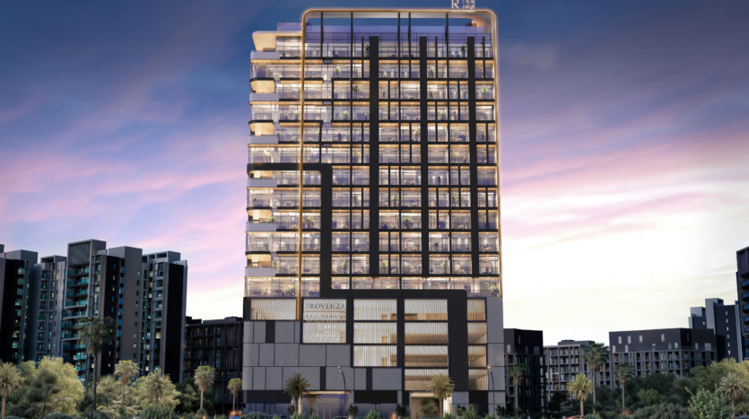 A modern multi-storey building with illuminated balconies and geometric architectural elements stands against a twilight sky, surrounded by palm trees and other contemporary buildings at Provenza Residences Dubai.