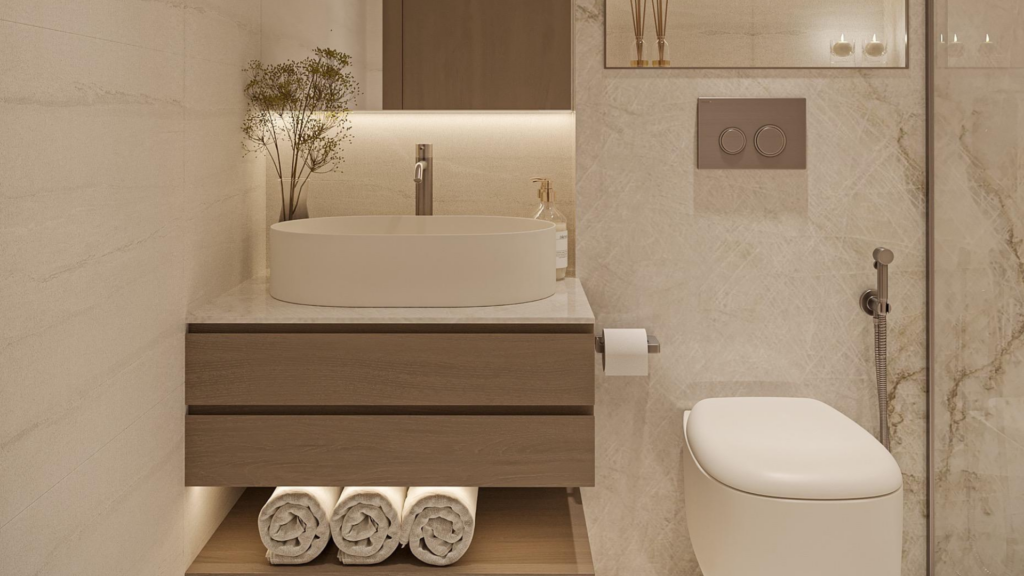 Modern bathroom at Provenza Residences Dubai featuring a round white sink on a wooden vanity, rolled towels underneath, wall-mounted toilet, neutral marble walls and subtle recessed lighting for a warm atmosphere.