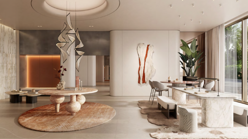 The modern, elegant lobby features marble floors, abstract sculptures, a round table, plush carpets and seating areas. Large windows let in natural light, while plants and artwork decorate the space.
