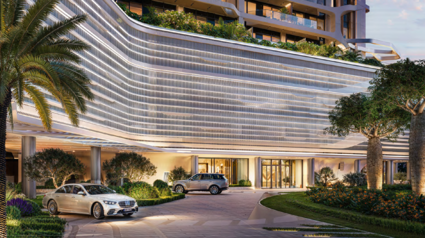 A modern luxury hotel entrance with elegant architectural design, illuminated curved lines, lush landscaping and two parked cars - a white sedan and a silver SUV - near the glass entrance.