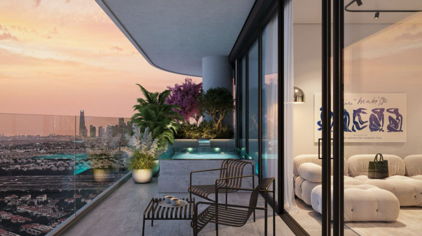 A modern balcony with glass balustrades, potted plants and a small pool overlooks the city at sunset. Two black chairs and a table are next to a comfortable indoor lounge with plush seating and contemporary artwork.