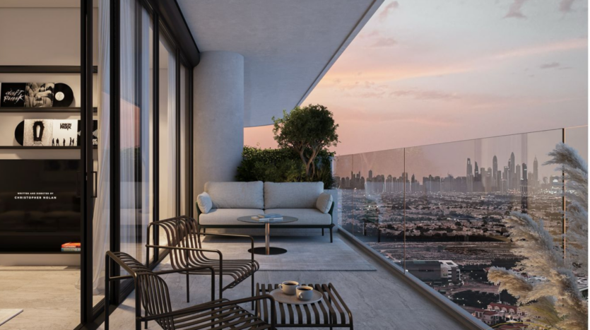 Modern sunset balcony with glass balustrade, small sofa, two striped chairs, round table and potted plants. The city skyline is visible in the distance under a colorful sky.