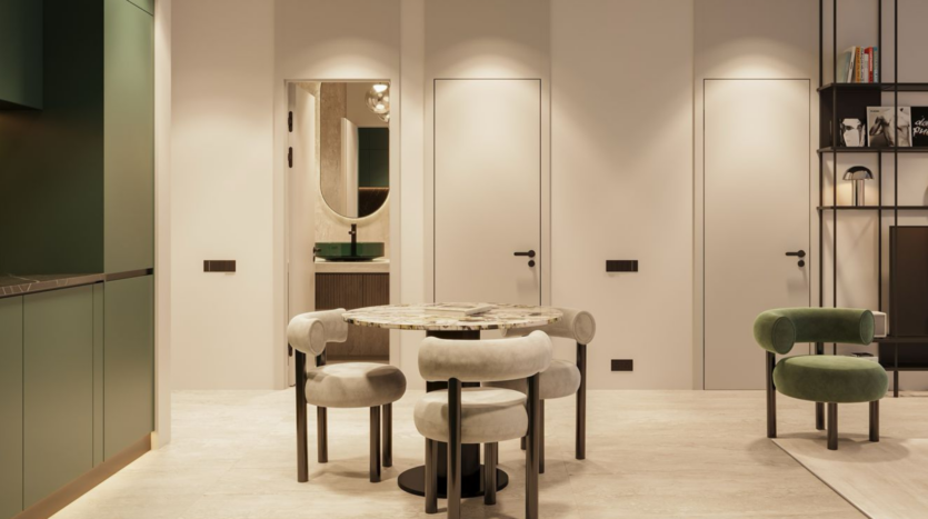Modern, minimalist dining room with a round marble table and four upholstered chairs, on beige walls. There are three closed doors, a green kitchenette on the left and open shelving on the right.