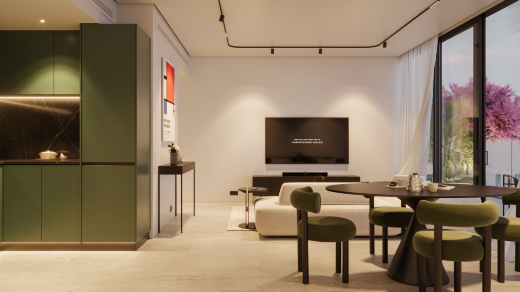 A modern open-plan living room and kitchen with green cabinetry, a round dining table, green chairs, a wall-mounted TV and large windows that let you see pink-leaved trees outside. The space is well-lit and minimalist.