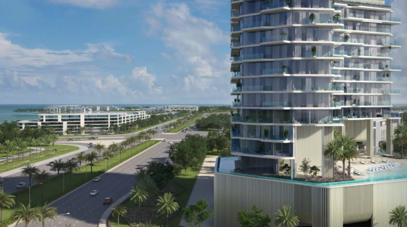A modern high-rise building with glass balconies overlooks a wide palm-lined road on Octa Island, on the island of Dubai, with more contemporary buildings and the ocean visible in the background under a partly cloudy sky.