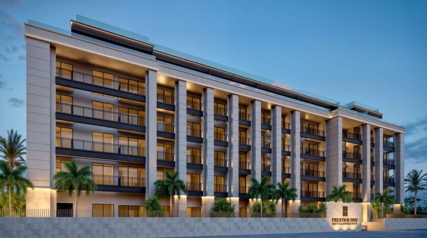 Modern multi-storey building with large balconies and tall columns, nestled among palm trees. A sign reading "Prestige Pink by PTLPL DEVELOPMENT" marks the entrance, evoking the elegance of Berkeley Square Prestige One under the clear evening sky.