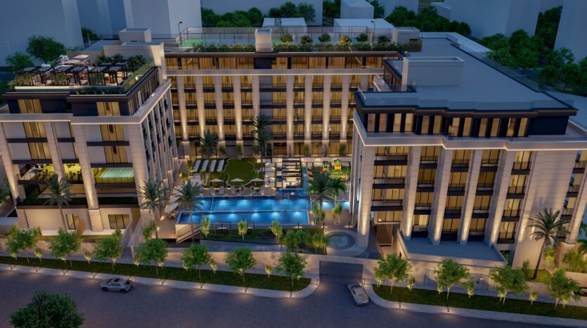Aerial view of Berkeley Square Prestige One at night with illuminated windows, outdoor pool, palm trees, rooftop terrace and carefully landscaped surroundings along an illuminated street.
