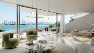 Camera da letto e soggiorno moderni, a pianta aperta, con vetrate che si affacciano sullo skyline della città e sul lungomare. Include due sedie verdi, un tavolino in marmo e un letto accanto a un ampio balcone.