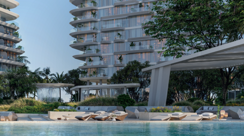 Modern luxury apartment buildings with curved balconies and greenery, overlooking a serene pool with sun loungers, shaded pergola, lush landscaping and water fountain in a tropical setting.
