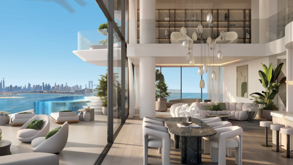 A modern, luxurious living and dining room with floor-to-ceiling windows overlooks a large balcony, infinity pool and ocean. Elegant furniture, plants and hanging lamps enhance the bright, airy space. The city skyline in the distance.