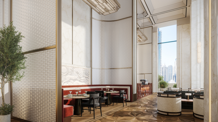 Elegante interno del ristorante del Waldorf Astoria Business Bay di Dubai, con soffitti alti, grandi finestre, pareti in marmo e schermi divisori. Sedute imbottite rosse e bianche circondano tavoli con ripiani in vetro, mentre la luce naturale inonda lo spazio.