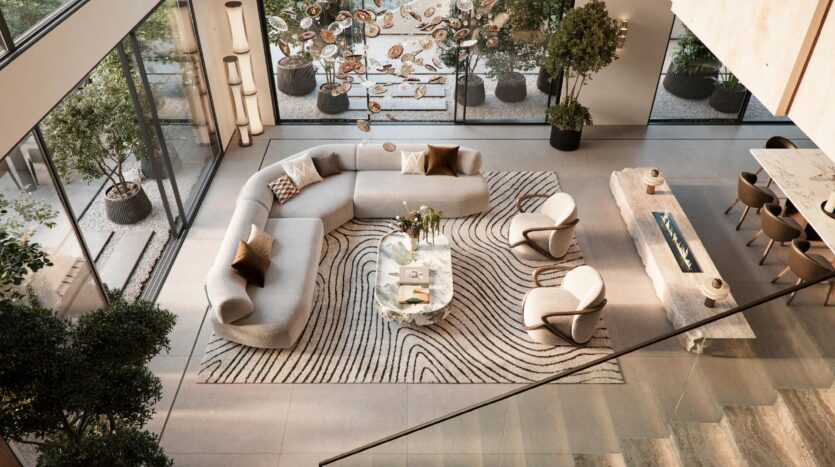 Un soggiorno moderno e spazioso con ampie finestre è arredato con un divano componibile grigio curvo e poltrone di Talea by Beyond, un tappeto a motivi, piante da interno e un tavolino in vetro; la luce naturale riempie la stanza.