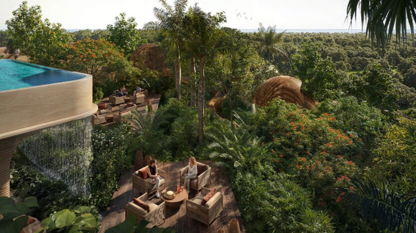 Una lussureggiante lounge sul tetto del Talea by beyond, dove ci si può rilassare su moderni arredi da esterno in mezzo a una fitta vegetazione tropicale e alberi, con una piscina a sfioro e una cascata sulla sinistra, con vista su un vasto paesaggio forestale.
