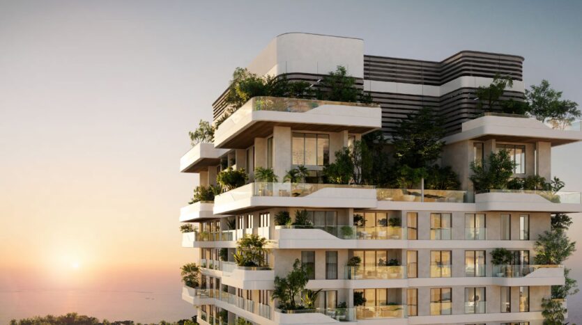 Un moderno edificio di appartamenti con balconi multipli ornati da una vegetazione lussureggiante, sullo sfondo di un sereno cielo al tramonto. Talea by Beyond è caratterizzato da linee pulite e ampie finestre che offrono una vista ininterrotta sull'orizzonte.