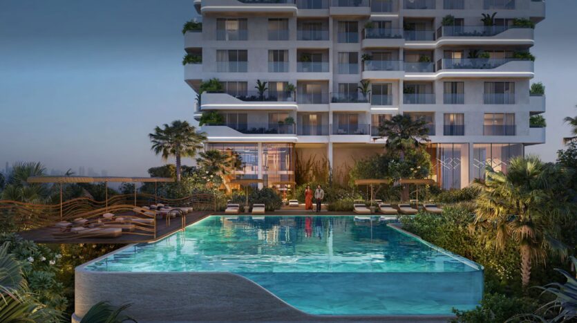 Un moderno condominio, Talea by Beyond, dispone di balconi che si affacciano su una grande piscina illuminata, costeggiata da palme e lettini al tramonto. All'ingresso della piscina si trovano due persone.