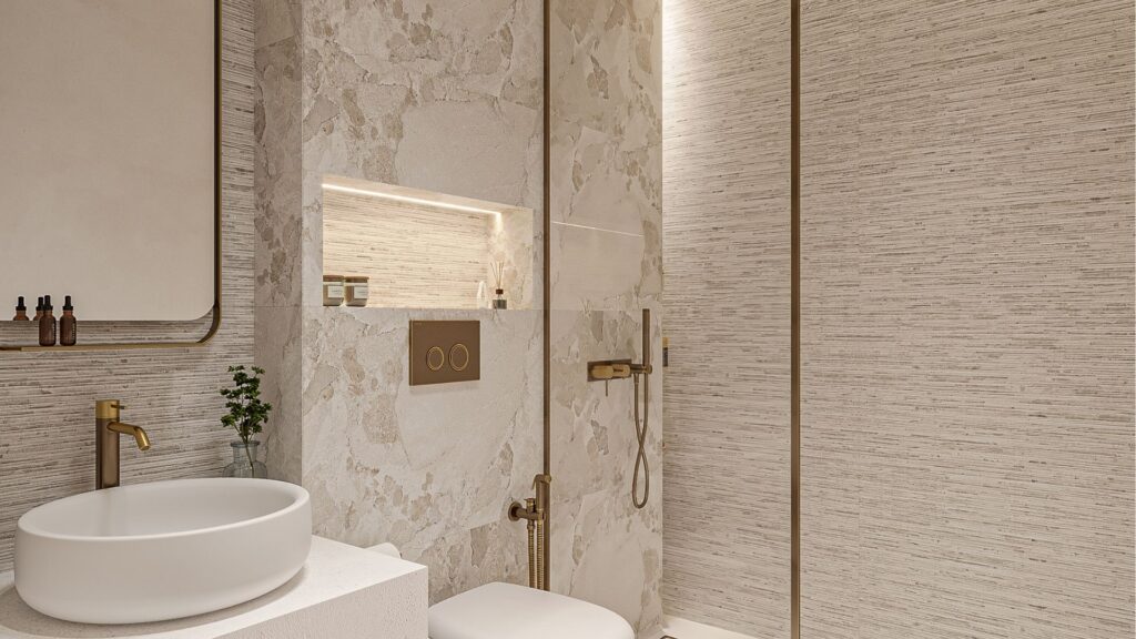 Salle de bains moderne avec des murs texturés beiges, un lavabo rond blanc, des luminaires dorés et une étagère encastrée contenant des articles de toilette belle vie zimaya, ainsi que des toilettes murales et une douche à l'italienne avec cloison en verre et pommeau de douche à effet de pluie.