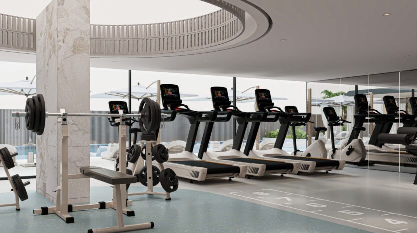 Une salle de sport moderne avec des tapis roulants, des bancs d'haltérophilie et divers équipements de remise en forme. De grandes fenêtres révèlent une piscine extérieure avec des parasols et des chaises longues. La conception lumineuse et spacieuse capture l'essence de la belle vie zimaya.