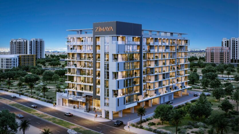 L'immeuble résidentiel moderne de moyenne hauteur "ZIMAYA" offre une belle vie avec ses balcons, ses grandes fenêtres et son éclairage du soir, dans une zone urbaine entourée de verdure, de routes et d'autres bâtiments en arrière-plan.