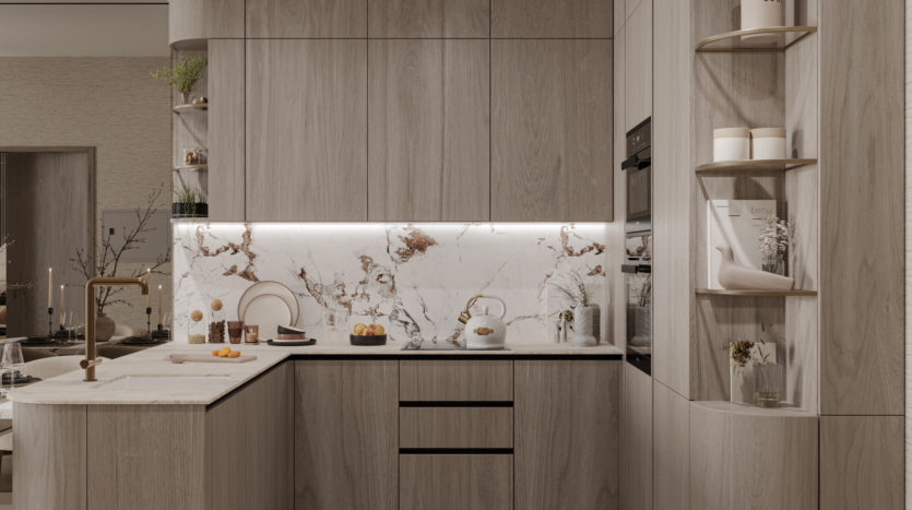 Cocina moderna con armarios de madera clara, salpicadero y encimera de mármol, grifería dorada, horno empotrado, estanterías abiertas con elementos decorativos e iluminación suave bajo los armarios. La vajilla y la fruta están ordenadas en las encimeras.