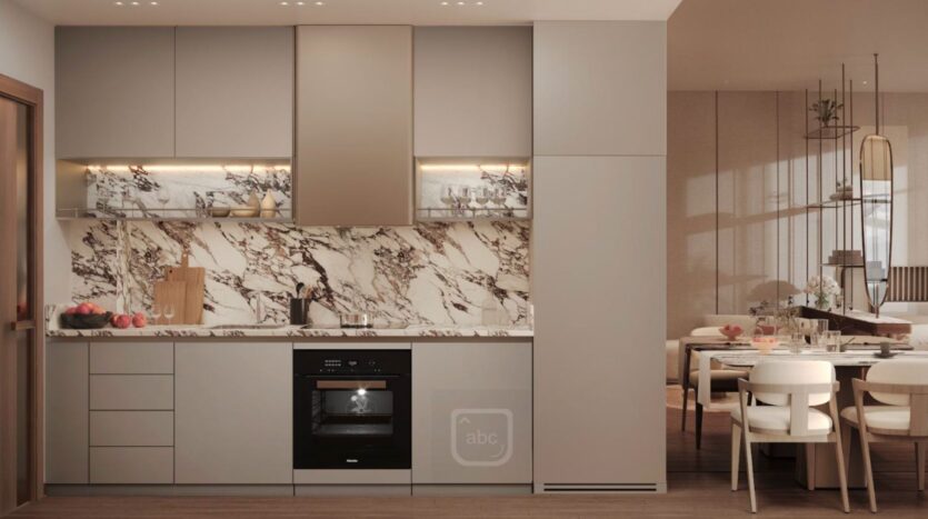 Modern kitchen with light gray cabinetry, marble backsplash, built-in oven and minimal appliances at Marquis One Arjan. The dining table with white chairs is visible on the right in this open living space.