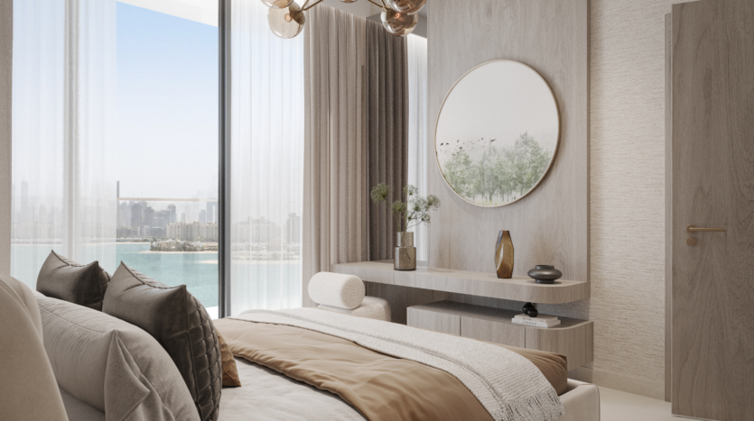 Un dormitorio moderno y minimalista con tonos neutros, una cama tamaño king, un espejo redondo sobre una elegante cómoda y ventanales que ofrecen vistas al agua y al lejano horizonte de la ciudad.