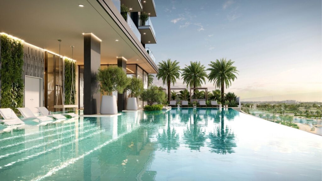 Modern rooftop infinity pool at Riverton House by Ellington Properties, surrounded by lush palm trees, sun loungers partially submerged in the water and views of the distant landscape under clear skies.