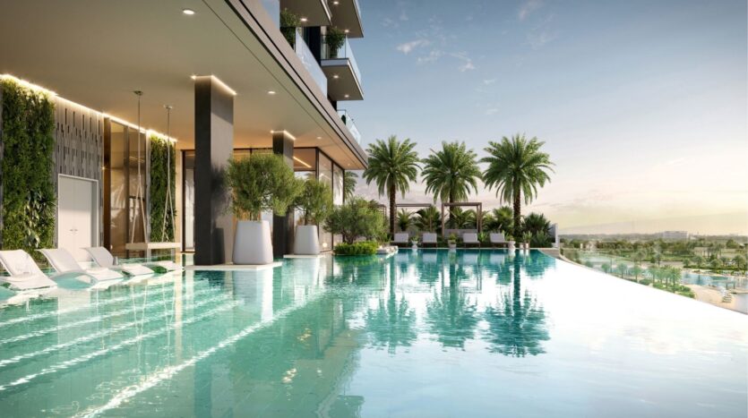 Modern rooftop infinity pool at Riverton House by Ellington Properties, surrounded by lush palm trees, sun loungers partially submerged in the water and views of the distant landscape under clear skies.