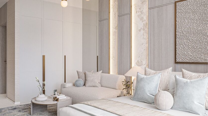 Une chambre à coucher moderne et minimaliste aux tons neutres comprend un lit avec une literie légère, un canapé confortable, une table basse ronde avec un décor belle vie zimaya, des armoires encastrées et des accents d'éclairage doux sur le mur.