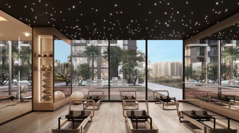 La salle de sport moderne de Windsor House de Ellington Properties est équipée de pilates reformers, de ballons d'exercice et d'haltères. Les fenêtres du sol au plafond donnent sur la piscine, les palmiers et la ville. Les plafonniers en forme d'étoile ajoutent de l'ambiance au milieu des gratte-ciel.