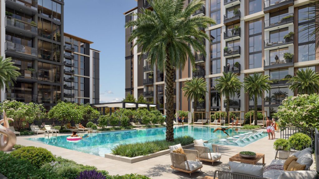 La cour d'un complexe d'appartements moderne à Windsor House de Ellington Properties comprend une piscine entourée de palmiers, de chaises longues et de personnes qui se détendent ou nagent. De grands bâtiments avec des balcons et de la verdure encadrent l'espace extérieur animé.